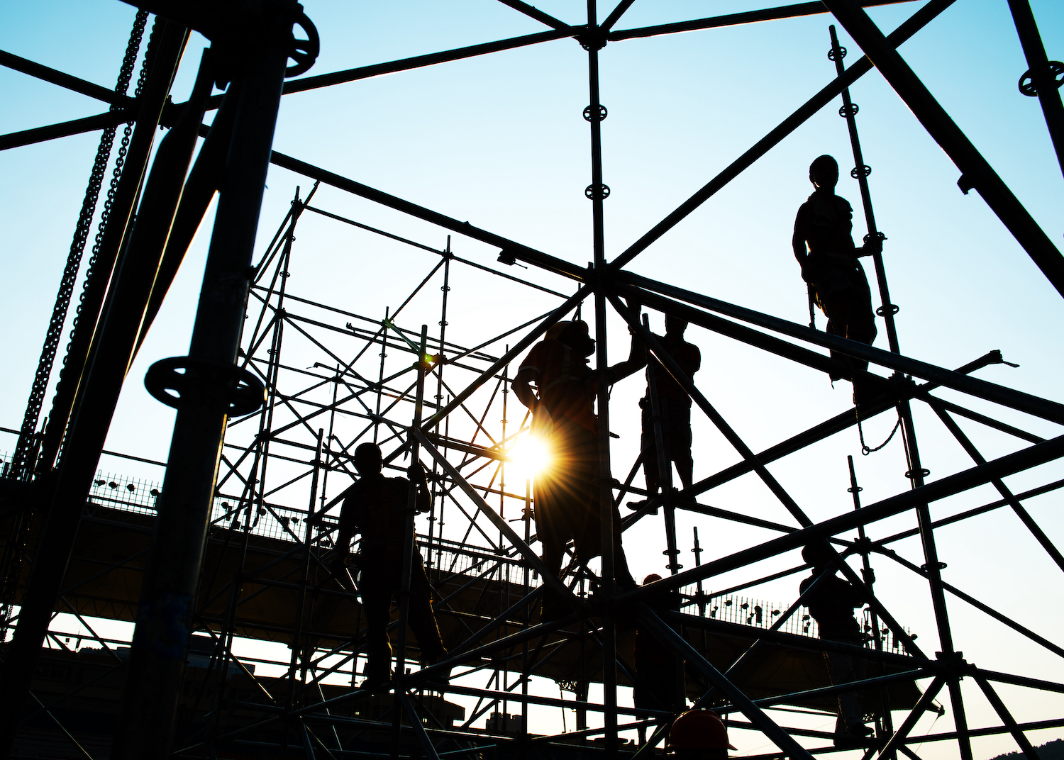 Construction workers stand high up on scaffolding on a construction site