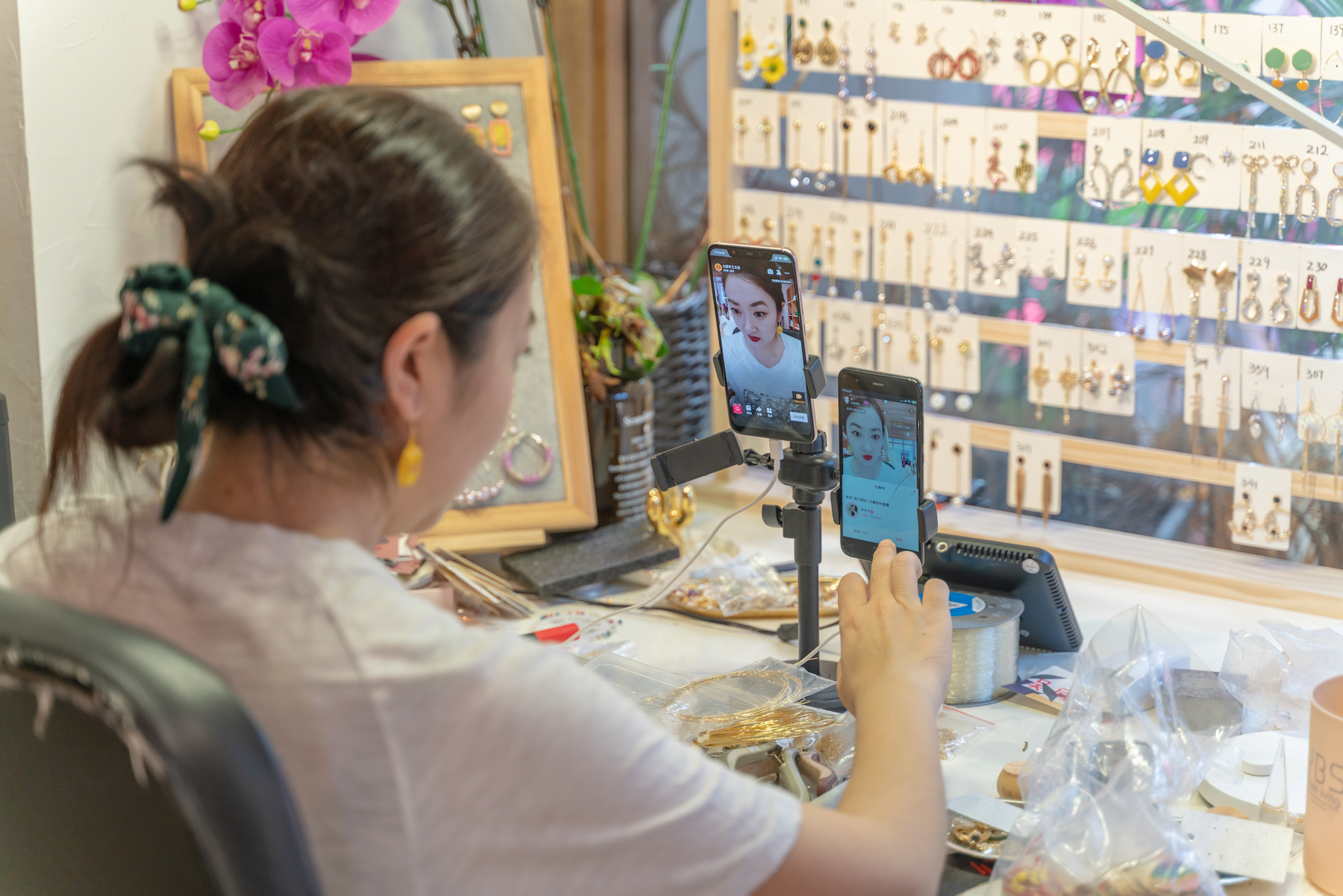 A woman with two phones prepares to livestream a jewellery sales event